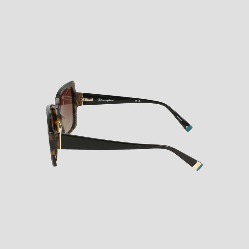 Side view of the Champion Women's Polarized Oversized Butterfly sunglasses with tortoiseshell frames, brown-tinted polarized lenses, thick black arms featuring a gold accent on the temple tips, and a small white Champion logo near the hinge, displayed against a plain light gray background.
