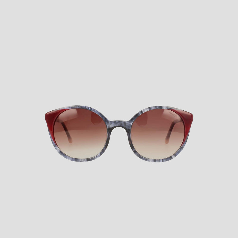The Champion Women's Polarized Flirty Round sunglasses feature gradient brown polarized lenses, marbled gray handmade acetate frames, and solid dark red accents on the upper corners, shown against a plain light gray background.
