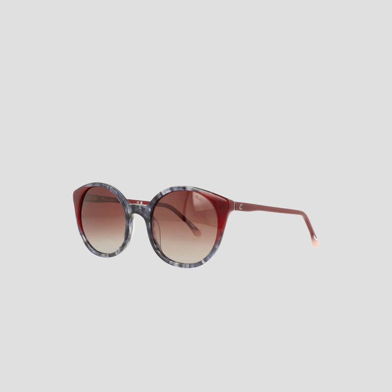 The Women's Polarized Flirty Round sunglasses by Champion, crafted from handmade acetate with red and gray marbled frames and brown gradient lenses, are displayed on a plain light background.