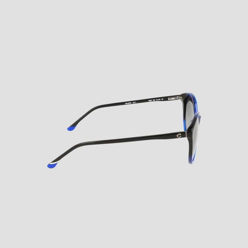Women's Polarized Flirty Round sunglasses by Champion are shown in a side view, featuring black cat eye frames with blue accents, highlighting the slim handmade acetate arms and elegantly curved temples against a plain light gray background.