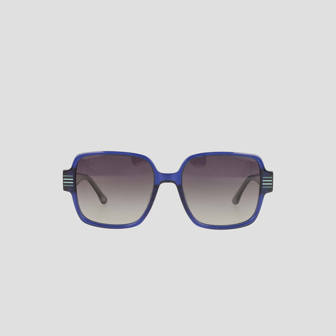 The Champion Women's Polarized Glam Square sunglasses feature an oversized square blue handmade acetate frame with dark gradient polarized lenses. Curved arms sport decorative stripes on the upper corners, set against a plain light background.