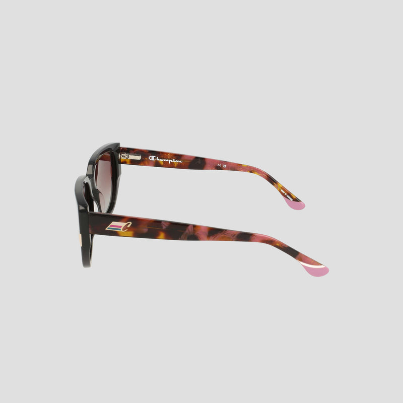Side view of the Champion Women's Polarized Modified Cateye sunglasses, featuring a tortoiseshell frame with pink tips and a subtle Champion logo on the arm, crafted from handmade acetate for a premium feel, displayed against a plain light gray background.