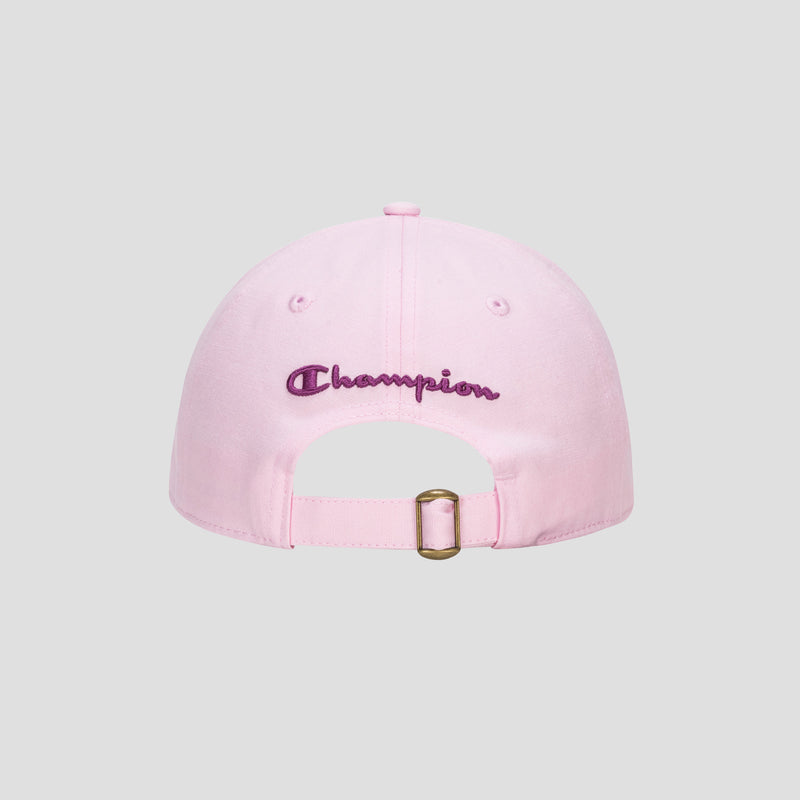 Introducing the Amber Chenille Adjustable Baseball Cap by Champion, crafted from premium slub canvas in a light pink hue. This unconstructed-fit cap features “Champion” embroidered in purple on the back and is designed with an adjustable strap and brass buckle. The cap is showcased against a plain gray background.