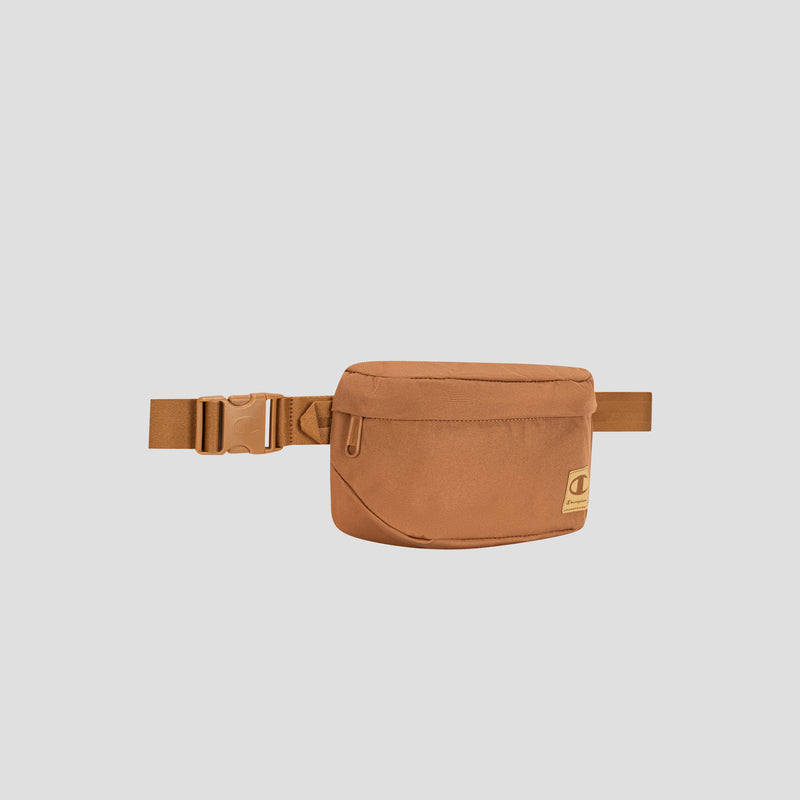 The Champion Atlas Waist Pack in tan, showcasing a front zipper pocket and an adjustable strap for hands-free convenience, is displayed against a plain light gray background.
