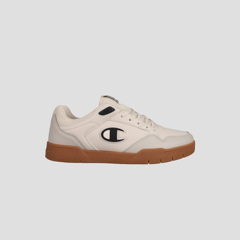 The Champion Men's Arena Lo V2 T is a cream-colored classic court sneaker with a brown rubber sole, lace-up front, and black and white C logo on the side. Displayed on a light gray background that highlights its heritage style.