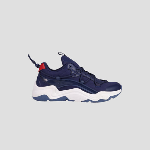 The Champion Men's Hyper C Pilot is a navy blue lifestyle sneaker with a durable mesh upper, chunky white and blue sole, dark blue laces, and a red heel accent, shown on a light gray background.