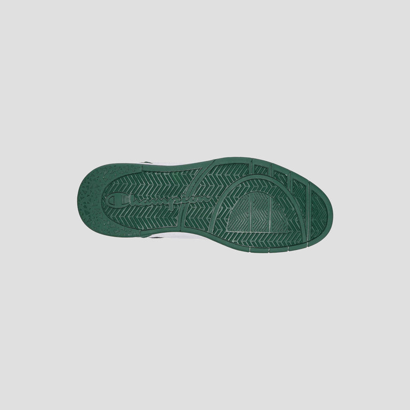 A green rubber sole of the Champion Men's 5-on-5 Low sneaker is shown from below, revealing its textured tread with lines and geometric shapes, emphasizing the minimalist style against a plain light gray background.