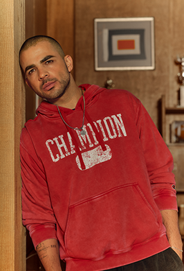 Man wearing a red Champion hoodie in an indoor setting
