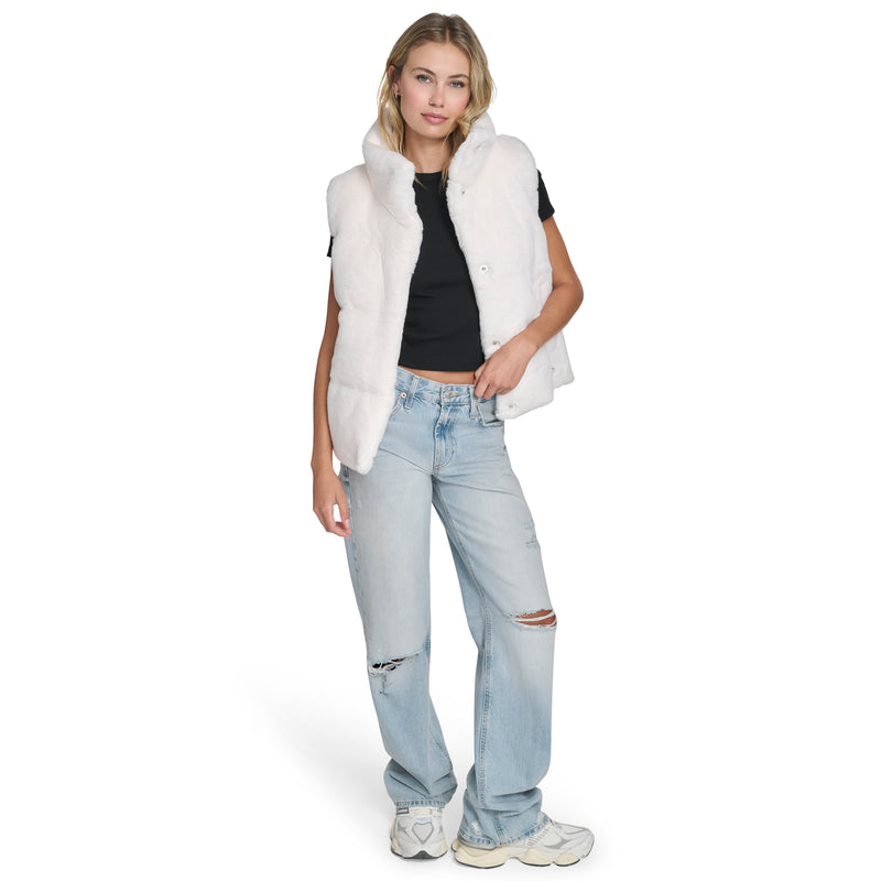 A woman models a Champion Puffer Vest over a black tee, paired with light blue ripped jeans and white sneakers against a white background, highlighting effortless cold-weather style in a relaxed pose.