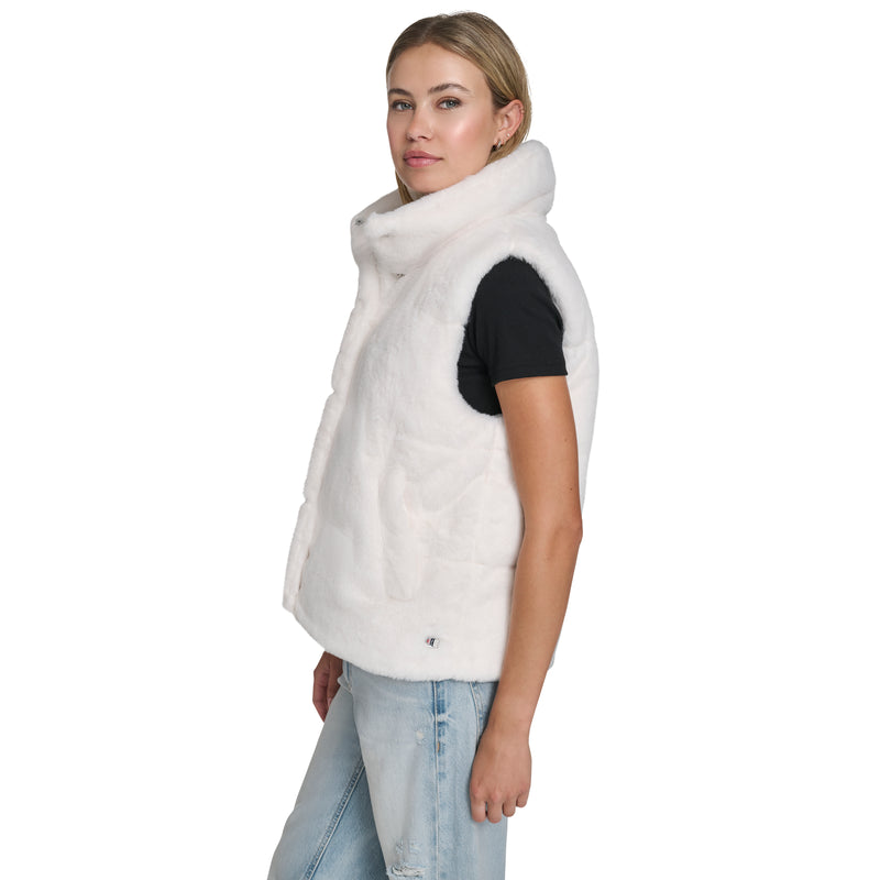 A woman models cold-weather style in a Champion Puffer Vest over a black tee and light blue distressed jeans, posed in profile against a white background.