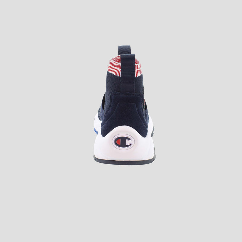 The Champion Men's Rally Pro slip-on sneaker in navy blue is shown from the back, with a white sole featuring the Champion logo, a red-and-white striped heel detail, a cushioned insole, and set against a plain light gray background.
