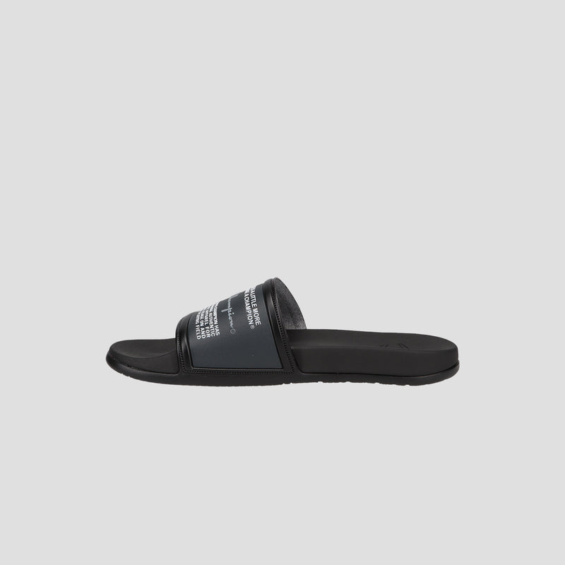 The Champion Men's IPO Squish Slide is a black sandal with a wide strap featuring white text. It has a flat sole, contoured footbed, open toe design, and is shown on a light gray background.