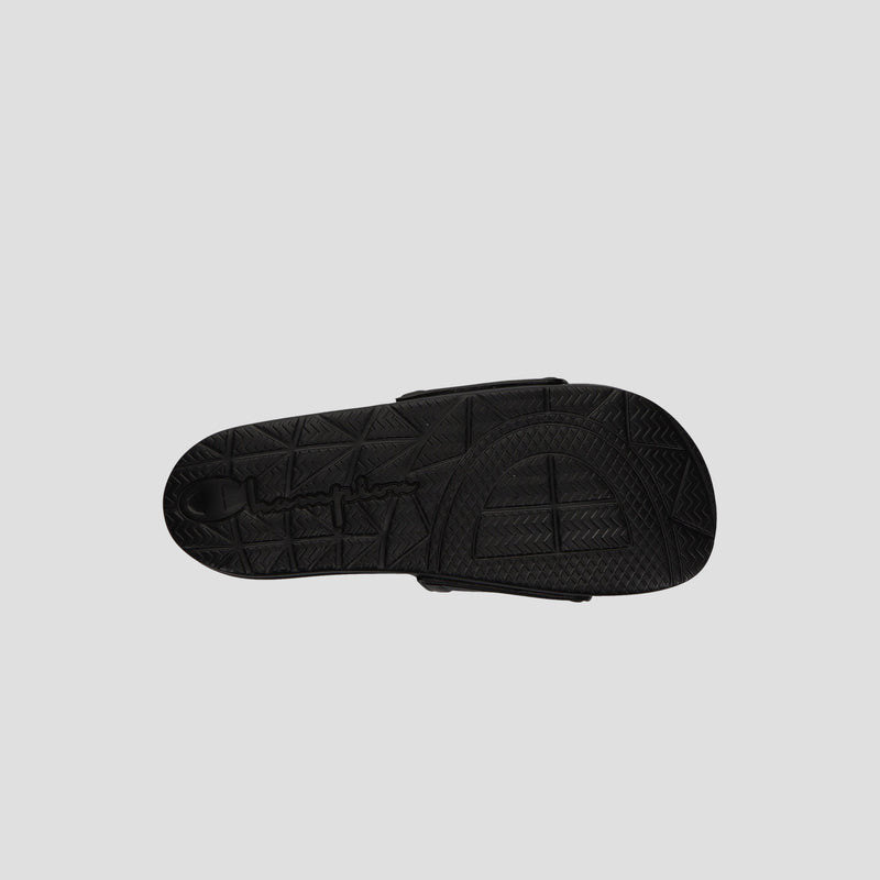 The image shows the bottom view of a black Champion Men's IPO Squish Slide sandal with a textured, geometric-patterned sole and embossed branding on a plain light gray background.