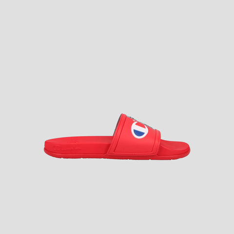 The Men's IPO Squish Slide by Champion features a red design with an open toe, wide strap, and the white and blue Champion logo. Lightweight slides with a contoured footbed for comfort, shown on a plain light gray background.