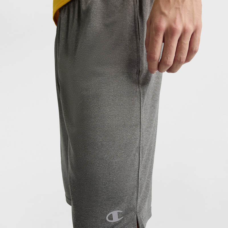 A person wears Champion 10" Moisture Wicking Sport Shorts in gray, with the logo near the hem, paired with a yellow top and their right hand by their side.