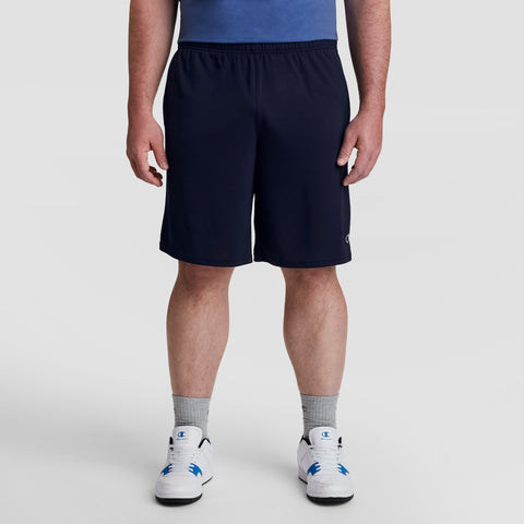A man stands facing forward against a plain white background, wearing a blue shirt, gray socks, white sneakers, and Champion 10" Moisture Wicking Sport Shorts - Big & Tall. His head is not visible in the image.