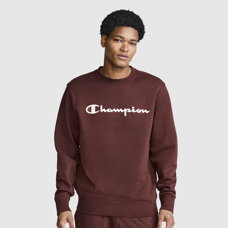 A person wearing a maroon Champion Powerblend Crewneck Sweatshirt, Classic Script Logo, along with matching pants stands against a plain light gray background, facing forward with a neutral expression. The cozy crewneck from Champion adds to the casual yet stylish look.