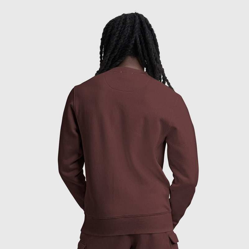 A person with long, dark, braided hair is shown from the back against a plain light gray background, wearing a maroon Champion Powerblend Crewneck Sweatshirt with Tonal Script Logo and matching pants.