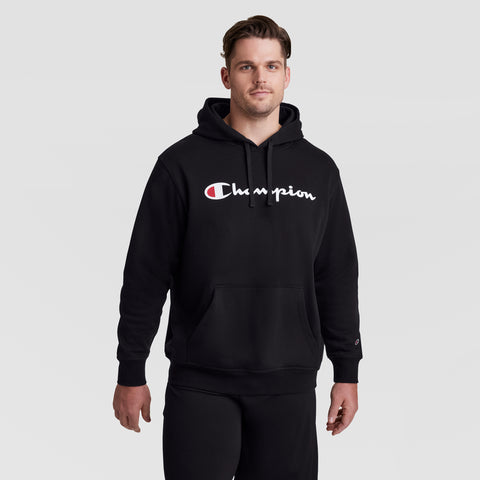 A man wears the Champion Powerblend Hoodie, Full Script Logo - Big & Tall, featuring the white and red Champion logo across the chest, standing against a plain light gray background.