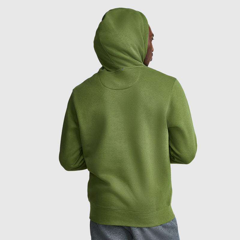A person wearing a Champion Powerblend Hoodie, Full Script Logo in olive green and gray pants is shown from the back, standing against a plain light gray background.