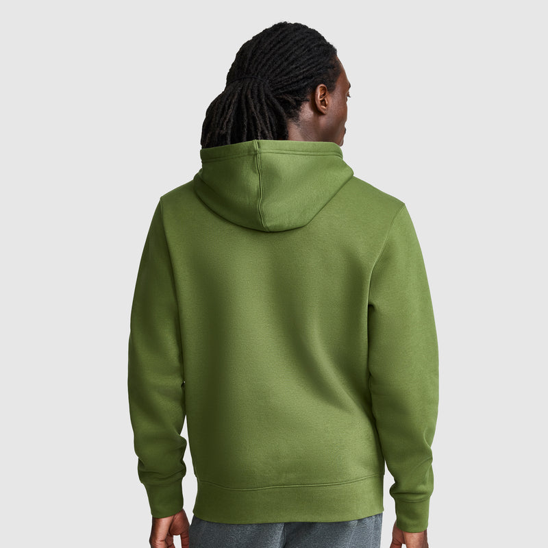 A person with long, dark hair is shown from the back, wearing a Champion Powerblend Hoodie with Full Script Logo in green and gray pants, standing against a plain light gray background.