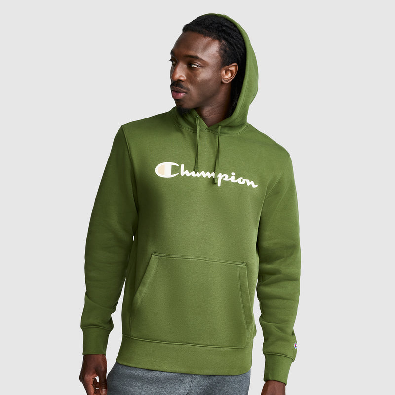 A man wearing a green Champion Powerblend Hoodie, Full Script Logo, featuring a front pocket and hood, looks to his left against a plain light gray background.