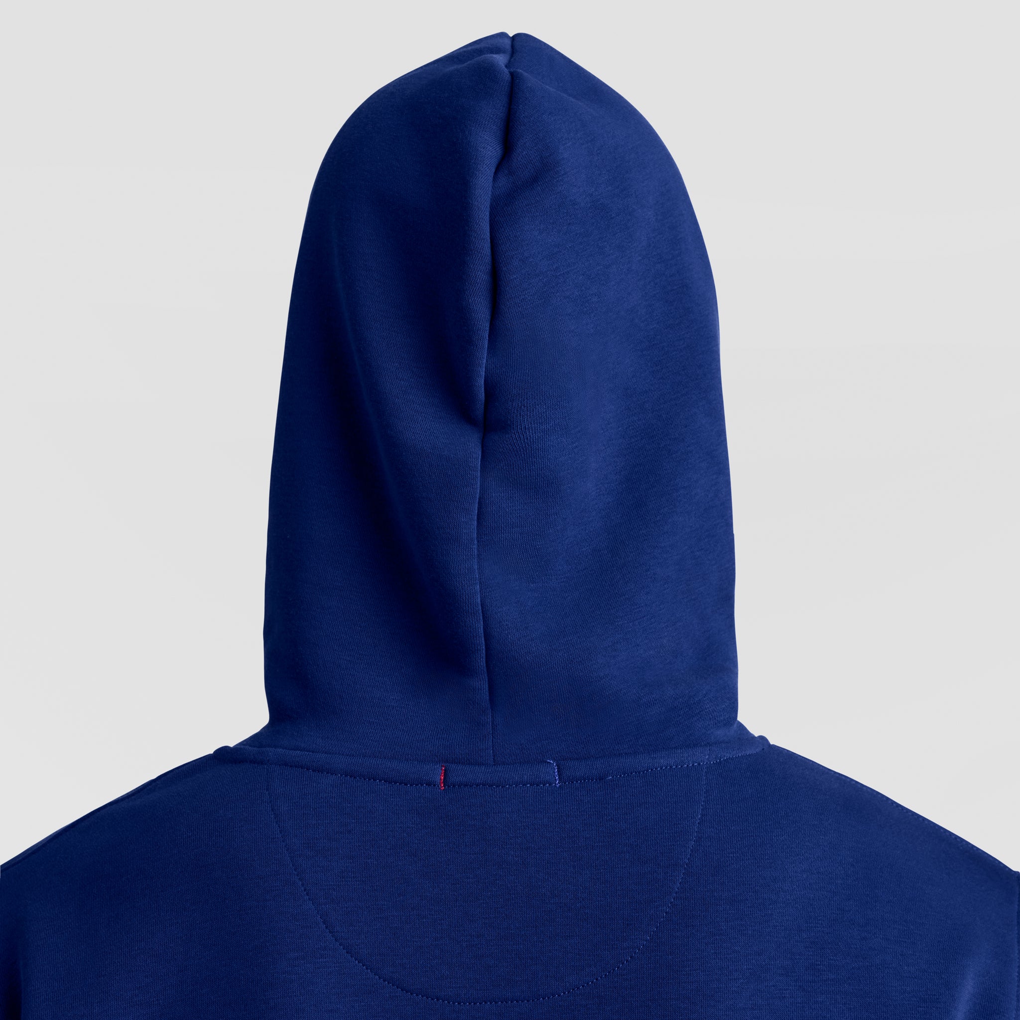A close-up of the Champion Powerblend Hoodie, Tonal Script Logo for men in deep blue, with the hood up and tonal script logo on the back, set against a light gray background.