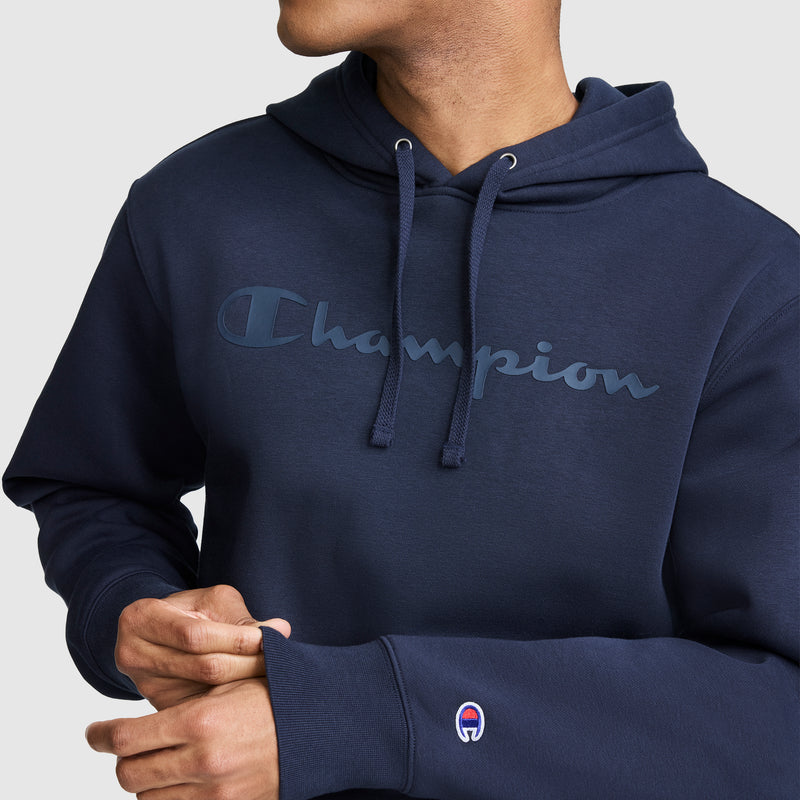 A person wearing the Champion Powerblend Hoodie with a tonal script logo across the chest and a small Champion emblem on the sleeve. Made from soft Powerblend Fleece, they are adjusting the sleeve with one hand.