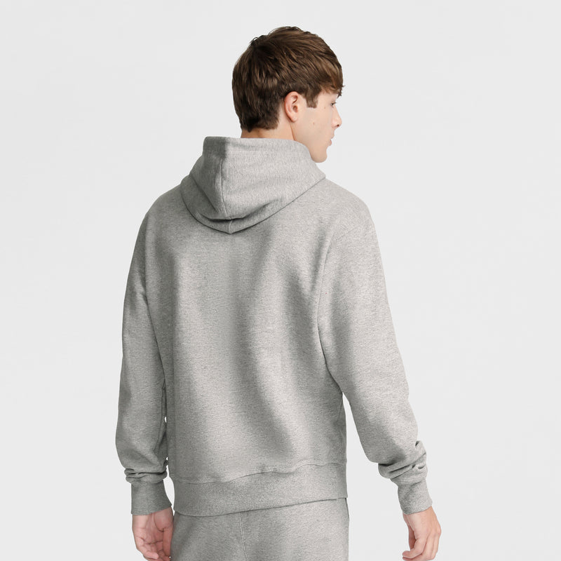 A young man with short brown hair is wearing a Champion Powerblend Hoodie, C Logo and matching gray sweatpants, facing away from the camera against a plain white background.