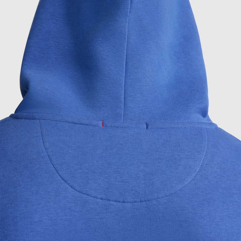 Close-up of the back of a blue Champion Powerblend Hoodie, C Logo, highlighting the stitching details and a small red thread near the top center of the hood.