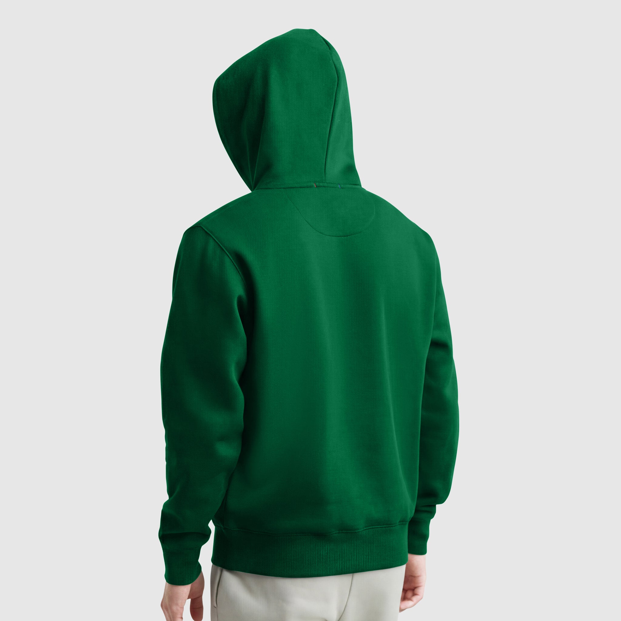 A person wearing a green Champion Powerblend Hoodie, C Logo, with the hood up, seen from the back against a plain light gray background.