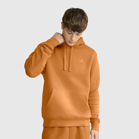 A person wearing a Champion Powerblend Hoodie, C Logo, along with matching sweatpants, stands against a plain light gray background while looking down and touching the side of their neck.