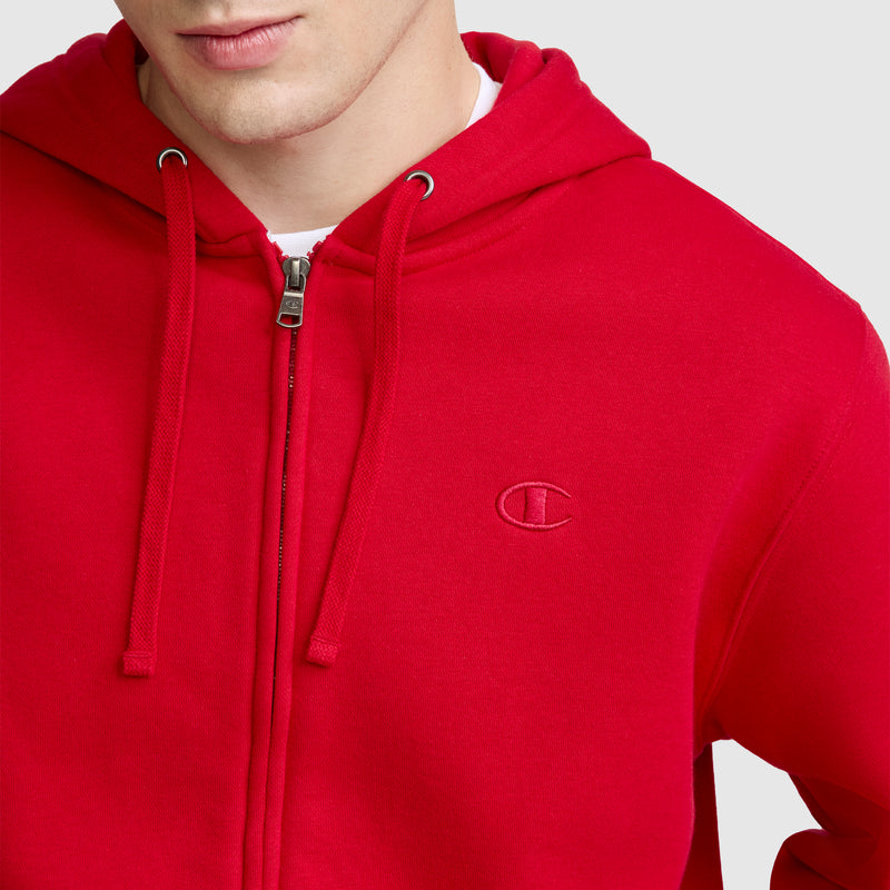 A person is shown from the shoulders up against a plain background, wearing the Champion Powerblend Full-Zip Hoodie, C Logo in bright red with a small embroidered logo on the left chest, paired with Champion Men's Powerblend Sweatpants featuring a cinched bottom.