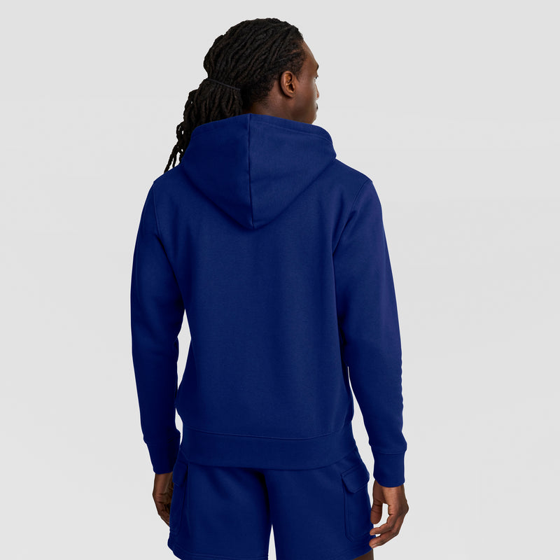 A person with long, dark, braided hair is shown from the back, wearing the Champion Powerblend Full-Zip Hoodie, C Logo in blue and matching blue shorts against a plain light background.