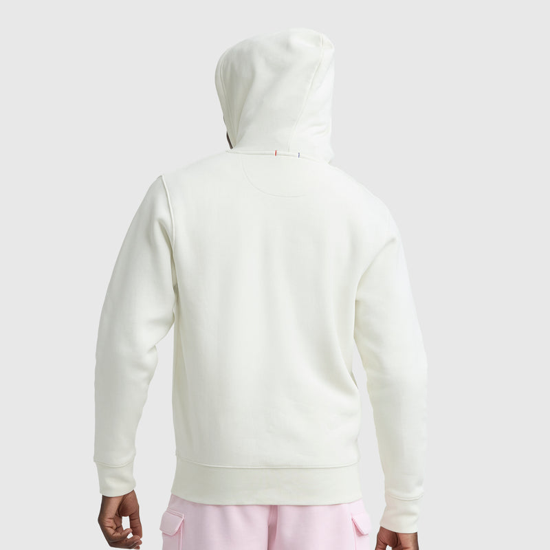 A person is seen from the back, wearing a white Champion Powerblend Full-Zip Hoodie, C Logo, with light pink pants, standing against a plain light gray background.