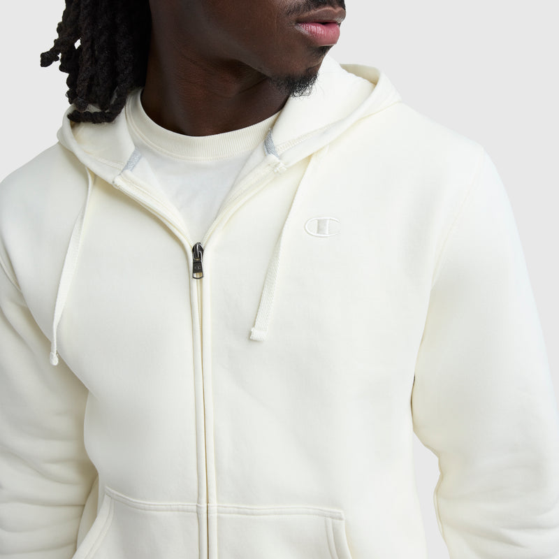 A person wearing a Champion Powerblend Full-Zip Hoodie, C Logo, over a white shirt. The Champion logo is embroidered on the chest. The image shows their upper body and part of their face turned to the side.