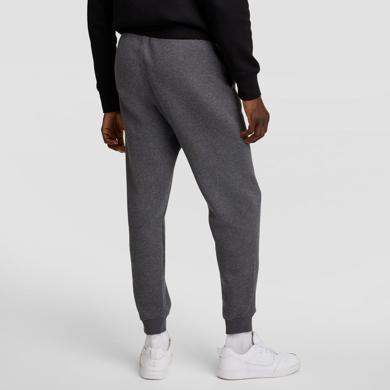 A person is shown from the back wearing Champion Powerblend Joggers, C Logo in dark gray, paired with a black sweatshirt and white sneakers against a plain light gray background.