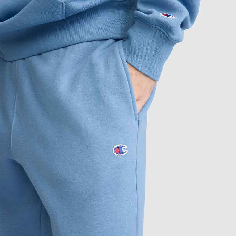 A person is wearing Champion's Powerblend Joggers with a matching light blue sweatshirt, one hand in the pocket. The signature C Logo from Champion is visible on both the joggers and the sleeve, emphasizing the cozy appeal of these fleece pants.