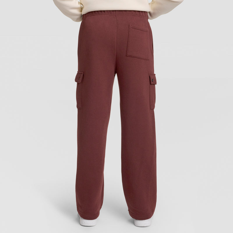 A person wearing Champion Fleece Cargo Pant, C Logo in maroon, styled as streetwear with side and back pockets, stands against a plain light background. Only the lower half of the body is visible.