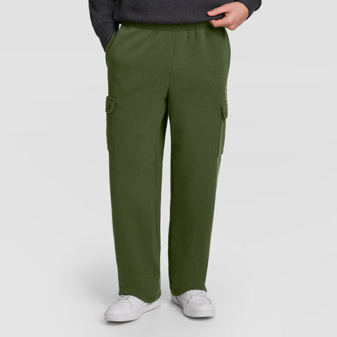 Dressed in Champion’s Fleece Cargo Pant, C Logo—a stylish olive green men’s cargo sweatpant inspired by streetwear—this individual pairs the look with a dark sweatshirt and white sneakers, standing with one hand in a pocket against a plain background.