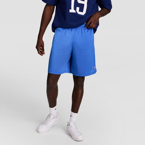 A person in a dark blue Champion sports shirt with the number 19, Champion 9" Classic Mesh Shorts (C Logo) in light blue, white socks, and white sneakers stands against a light gray background.