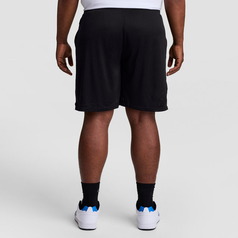 A person is standing facing away from the camera against a plain light background, wearing white sneakers, black socks, a white shirt, and Champion 9" Classic Mesh Shorts with C Logo - Big & Tall.