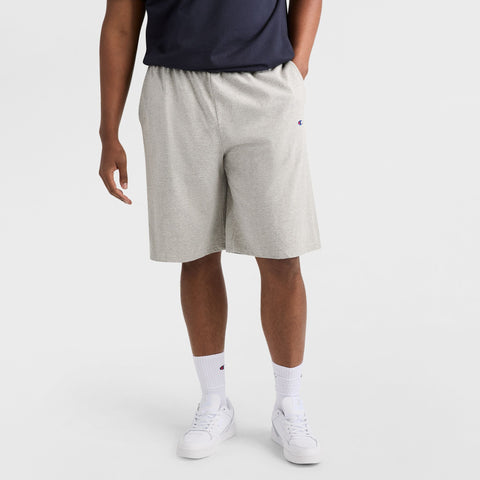 A person wearing Champion 9" Lightweight Lounge Shorts, C Patch Logo - Big & Tall in light gray, styled with a navy shirt, white crew socks, and white sneakers stands against a plain white background. Only the lower half of the body is visible.