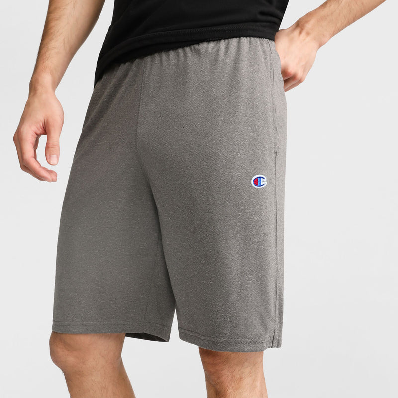 A person stands against a plain background, showcasing only their lower torso and upper legs while wearing Champion's 9" Lightweight Lounge Shorts with the C Patch Logo in gray. The Champion logo appears on the left thigh, emphasizing these comfortable shorts as an ideal choice for lounging or casual activities.