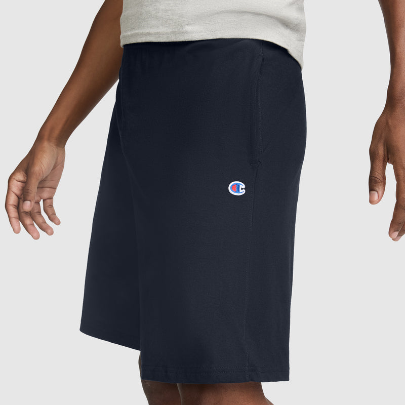 A person wearing Champion 9" Lightweight Lounge Shorts, C Patch Logo - Big & Tall in navy blue, featuring the signature small Champion logo on the left thigh, paired with a light-colored shirt.