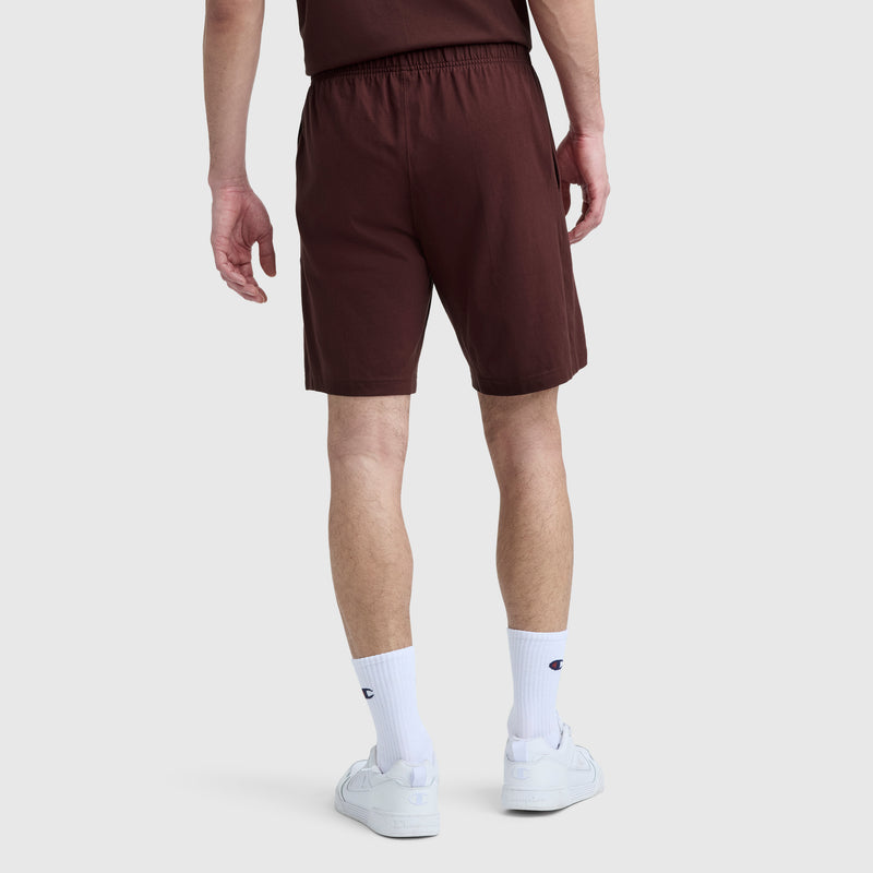 A person shown from the back against a plain light background wears the Champion 9″ Lightweight Lounge Shorts with C Patch Logo in maroon, paired with a matching t-shirt, white crew socks, and white sneakers.