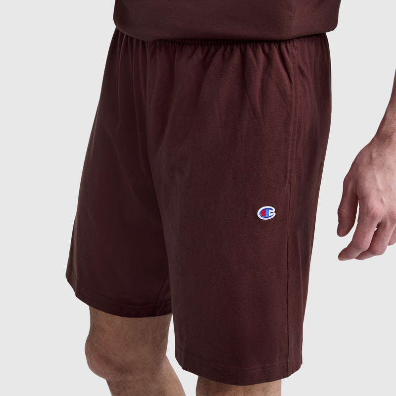 A person wearing Champion 9″ Lightweight Lounge Shorts, featuring an elastic waistband and a small C Patch logo on the left leg, stands against a plain light background.