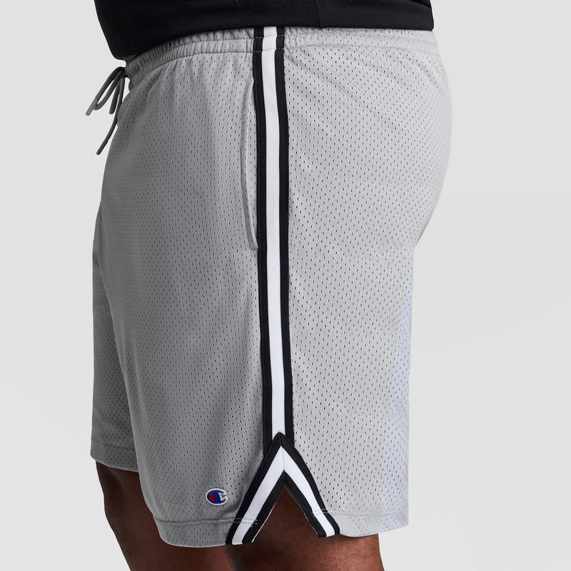 A person wears the Champion 10" Lacrosse Mesh Shorts - Big & Tall in light gray with black and white side stripes, a small Champion logo near the hem, and a comfortable drawstring waistband.