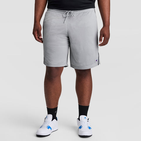 A person models Champion 10" Lacrosse Mesh Shorts - Big & Tall in light gray, paired with a black shirt, black socks, and white sneakers with blue accents against a plain light gray backdrop. Only the lower body is shown.