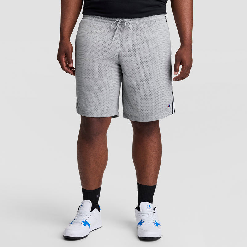 A person models Champion 10" Lacrosse Mesh Shorts - Big & Tall in light gray, paired with a black shirt, black socks, and white sneakers with blue accents against a plain light gray backdrop. Only the lower body is shown.